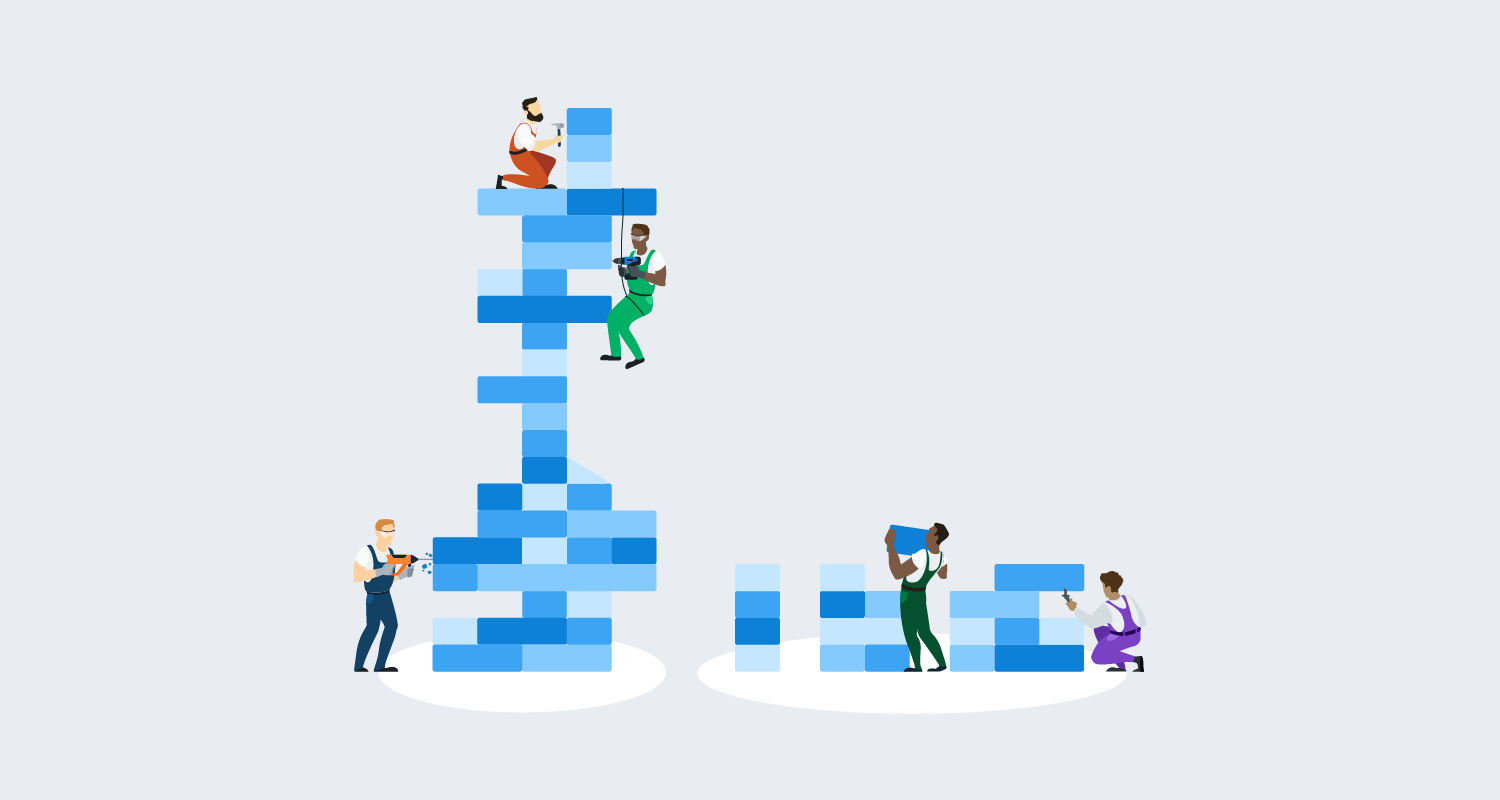 3 people building an unstable looking tower with blue blocks, beside 2 people building a stable, lower tower with blue blocks.